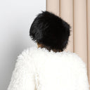 A person wearing a white furry coat and a black furry hat is facing away from the camera.